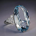 Schillernder blauer Zirkonring mit seitlichen Strass-Akzenten