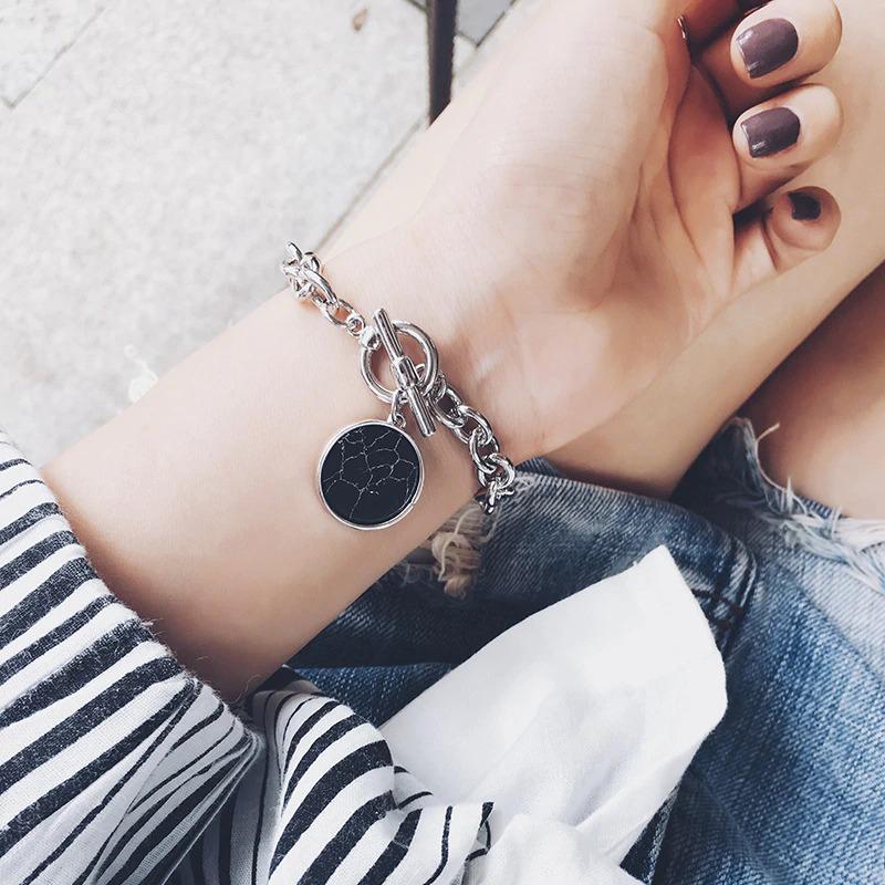 Halskette und Armband mit Anhänger aus glattem, schwarzem Marmor.